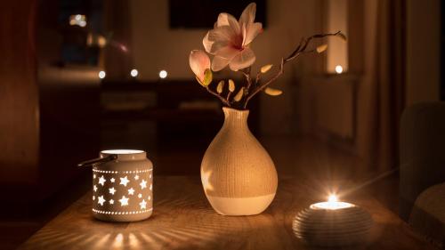 a table with a vase with flowers and a candle at Penzion Horska Kvilda in Horská Kvilda