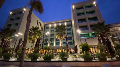 a building with palm trees in front of it at Royal G Hotel and Spa in Durrës