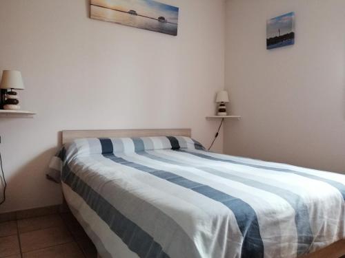 a bedroom with a large bed with blue and white sheets at Gite Les Garbails in Le Barp