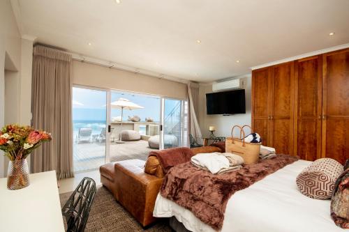 a bedroom with a bed and a couch and a balcony at Beach Villa Wilderness in Wilderness