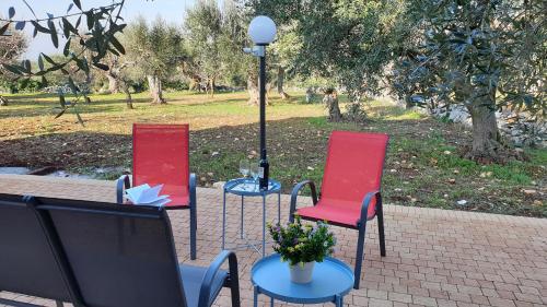 three chairs and a table with a lamp in a park at Tra gli ulivi in Putignano
