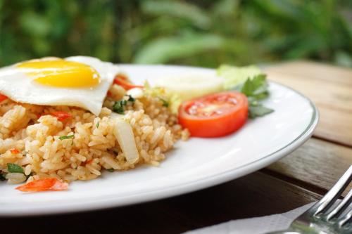 a plate of fried rice with an egg and tomatoes at Louto Dmell Guesthouse in Sanur