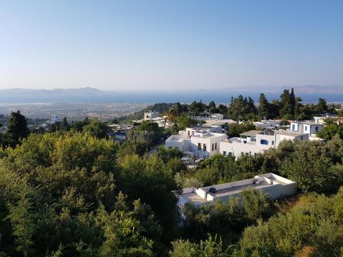 a group of white buildings on a hill with trees at Hestia in Kos