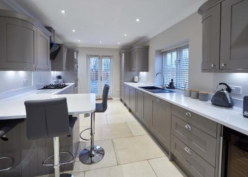 una cocina con armarios grises y encimeras blancas en Host & Stay - Lowcross Cottage, en Guisborough