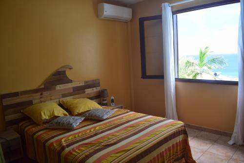 - une chambre avec un lit et une grande fenêtre dans l'établissement Blue Palms, à Saint-Leu