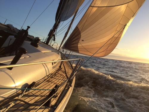 a sailboat in the ocean with the sunset in the background at Sands Hotell in Sandhamn