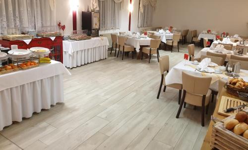 Waldhotel Rennsteighöhe في فراونوالد: غرفة طعام بها طاولات وكراسي بيضاء