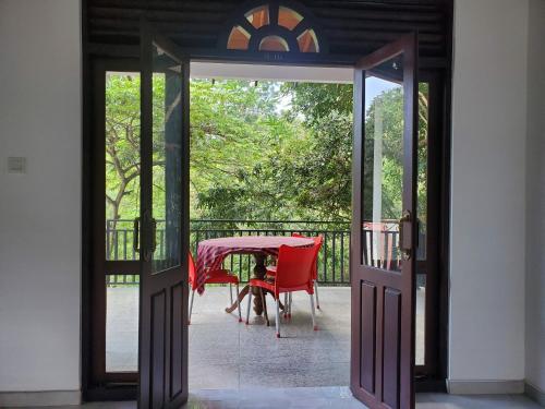 eine offene Tür mit einem Tisch und einem roten Stuhl in der Unterkunft Sigiriya River Side Villa in Sigiriya