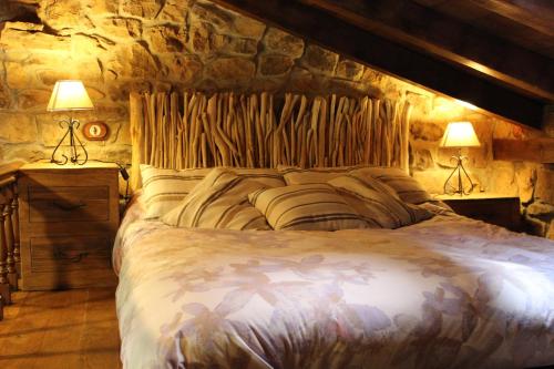 1 dormitorio con 1 cama grande en una pared de piedra en El Refugio de Luena en San Miguel de Luena