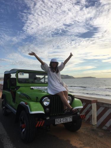 a woman sitting on the bonnet of a green jeep at Lang Chai Guesthouse in Mui Ne