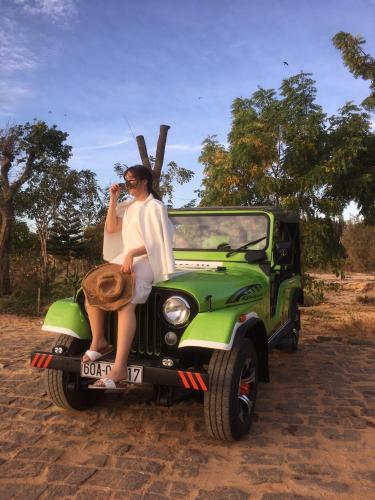 a woman sitting on the back of a green jeep at Lang Chai Guesthouse in Mui Ne