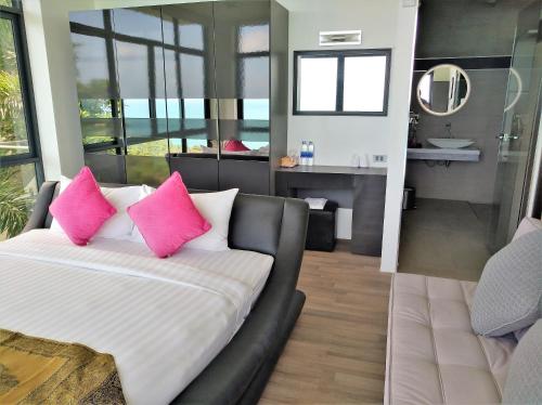 Un dormitorio con un sofá con almohadas rosas y un baño. en Villa Seawadee - luxurious, award-winning design Villa with amazing panoramic seaview, en Chaweng Noi Beach