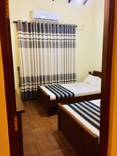 two beds in a room with a curtain at Sweet Home Tourist Rest, Cooking Classes & Tours in Anuradhapura
