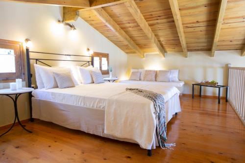 - duże białe łóżko w pokoju z drewnianym sufitem w obiekcie anerada / sun nature holidays w mieście Athanion