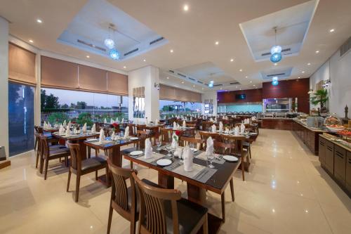 a restaurant with wooden tables and chairs and a kitchen at Ramada by Wyndham Beach Hotel Ajman in Ajman 