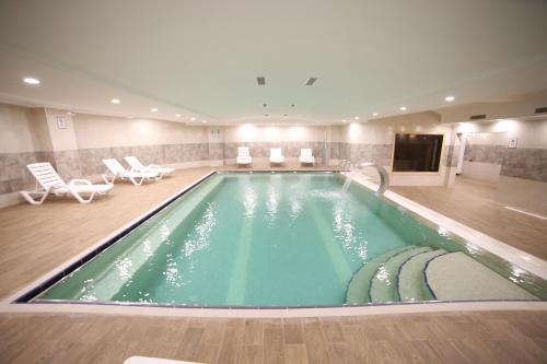 een zwembad in een hotel met stoelen en een tv bij EMA ÖZTÜRK THERMAL HOTEL in Afyon