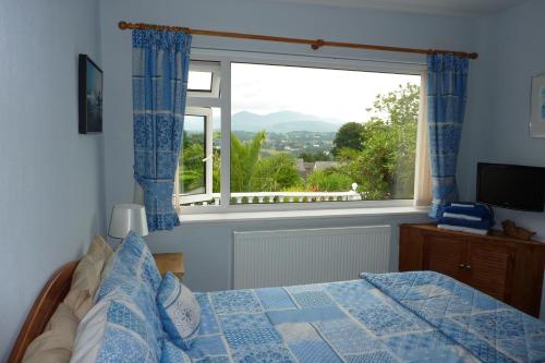 a bedroom with a bed and a large window at Eildon in Menai Bridge