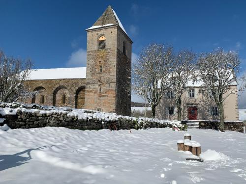 um edifício com uma torre de relógio na neve em L’Estive d’Aubrac em Aubrac