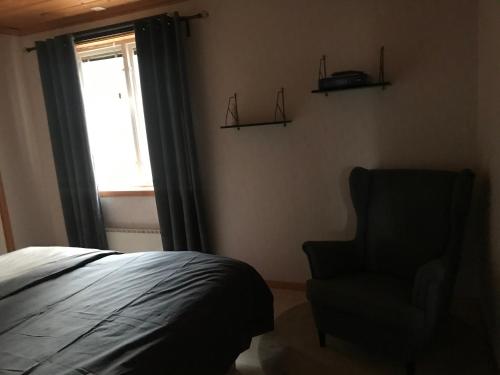 ein Schlafzimmer mit einem Bett, einem Stuhl und einem Fenster in der Unterkunft Backnäsgården in Sandöverken