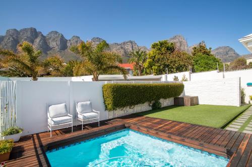 a backyard with a swimming pool with two chairs and a lawn at Funkey Villas Cape Town in Cape Town