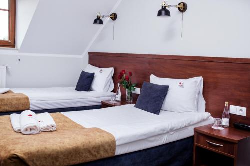 a hotel room with two beds and two tables at Hotel Trzy Róże in Lublin