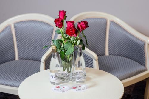 a table with two bottles and a vase of roses at Hotel Trzy Róże in Lublin