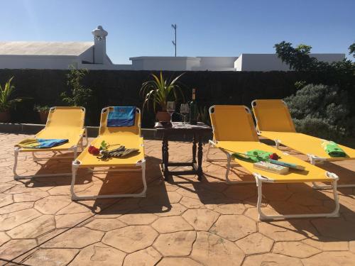 three yellow lounge chairs and a table with a bottle of wine at Casa Gloria in Tías