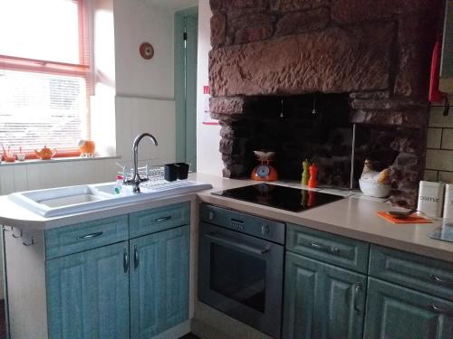 a kitchen with blue cabinets and a stone wall at Bank End in Egremont