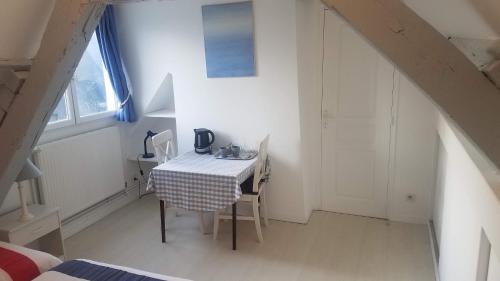 a small white room with a table and a window at Manoir de l'As de Trèfle in Isneauville