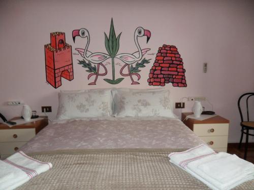 オリスターノにあるB&B Il Mirtoのベッドルーム1室(壁に花を飾ったベッド1台付)
