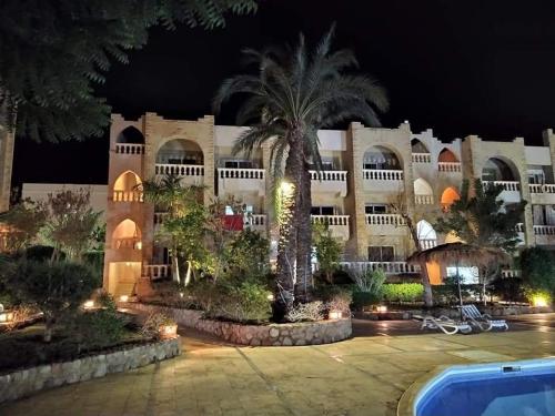 a large building with a palm tree at night at One- bedroom apartment S3 in Vip Zone Sunny Lakes in Sharm El Sheikh