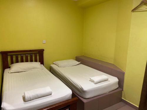 Hotel Rembau في Rembau: سريرين في غرفة صغيرة بجدران خضراء