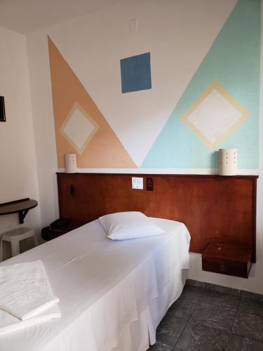 Schlafzimmer mit einem großen weißen Bett und geometrischen Decken in der Unterkunft Hotel Flamboiã in Araraquara