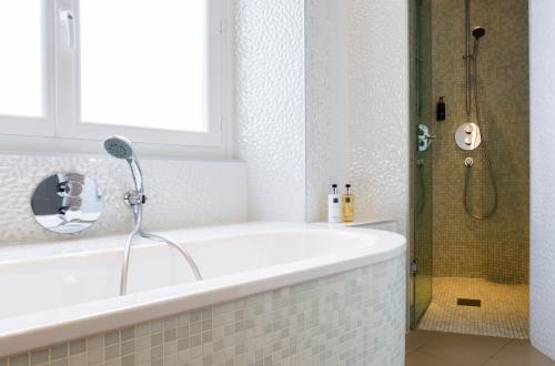a bath tub sitting next to a window in a bathroom at Oceania l'Hôtel de France Nantes in Nantes