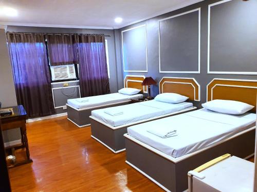 a room with three beds and a kitchen at Asiaten Hotel in Tarlac
