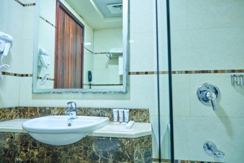 a bathroom with a sink and a shower with a mirror at Grand Square Hotel in Dubai