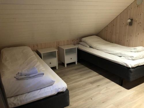 two beds in a room with two night stands at Rorbu Skreda in Leknes