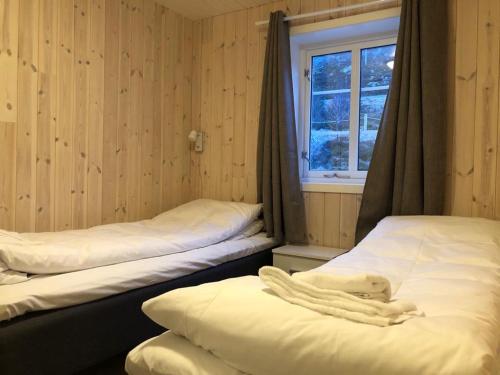 two beds in a room with a window at Rorbu Skreda in Leknes