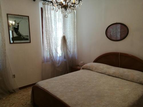 a bedroom with a bed and a chandelier and a window at Alberta in Bertiolo