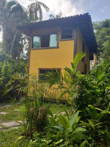 ein gelbes Haus inmitten eines Gartens in der Unterkunft Condominio Village Camburi in Camburi