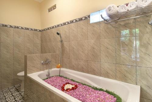 a bathroom with a bath tub filled with pink flowers at Jerogadung House in Ubud