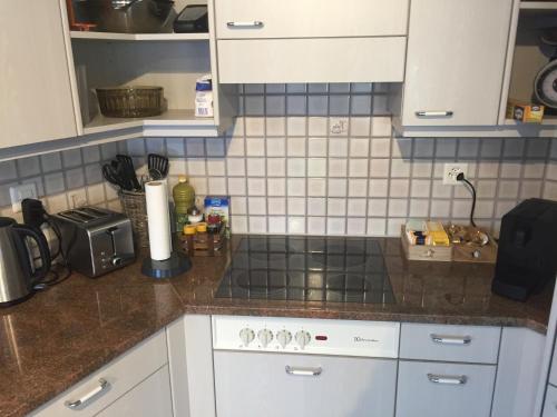 a kitchen with white cabinets and a stove top oven at Lake View Apartment in Faulensee