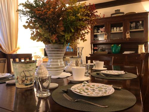 une table à manger avec des assiettes et un vase de fleurs dans l'établissement Le Tre Querce B&B, à Romano D'Ezzelino