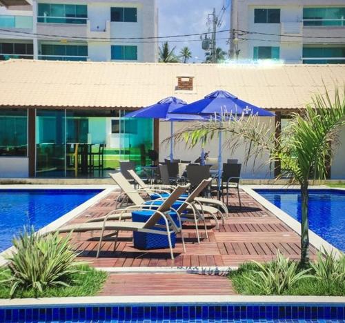 a pool with chairs and umbrellas next to a swimming pool at APARTAMENTO À BEIRA MAR - PÉ NA AREIA - Ilhéus in Ilhéus
