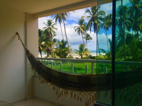 a hammock in a room with a view of the ocean at APARTAMENTO À BEIRA MAR - PÉ NA AREIA - Ilhéus in Ilhéus