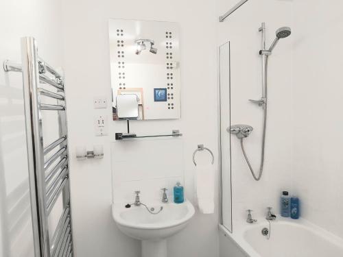 a white bathroom with a sink and a shower at Inverness City Centre Apartment with Elevator and Google Chromecast in Inverness