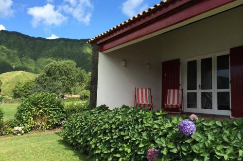 two red chairs sitting outside of a house at Lake Cottage - Panoramic views 7 Cidades in Sete Cidades