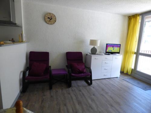 - deux chaises violettes dans une chambre avec un bureau et un ordinateur dans l'établissement Très bel appartement, à Saint-Lary-Soulan