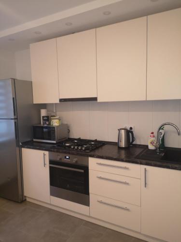 La cuisine est équipée de placards blancs et d'un four avec plaques de cuisson. dans l'établissement Parko apartamentai, à Panevėžys