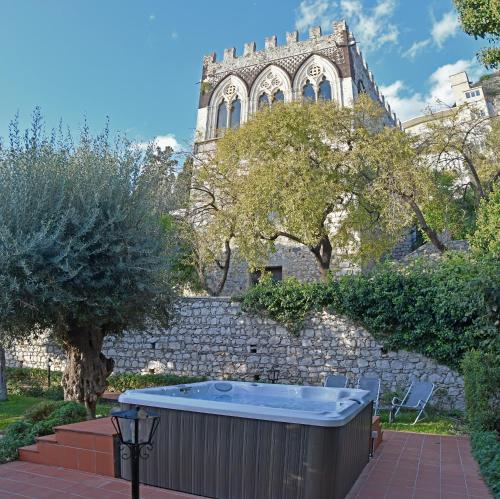 a hot tub in front of a stone wall with a building at Villa Siciliana in Taormina